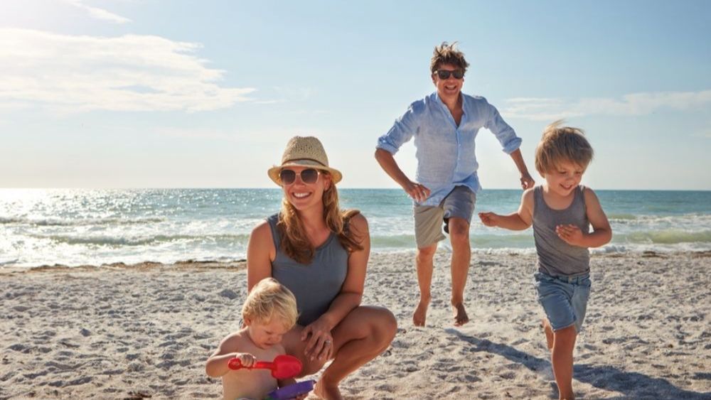 Husband and wife with two children playing in sand on beach